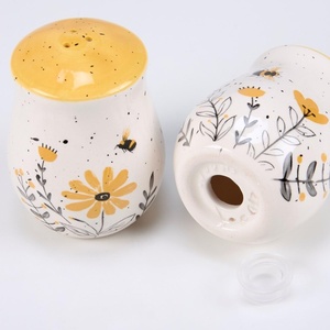 image:imagePrimitives by Kathy Salt amp Pepper Set  features bees buzzing over flowers with yellow accents Shakers include unique openings to tell them apart with plastic stoppers for easy refilling amp cleaning